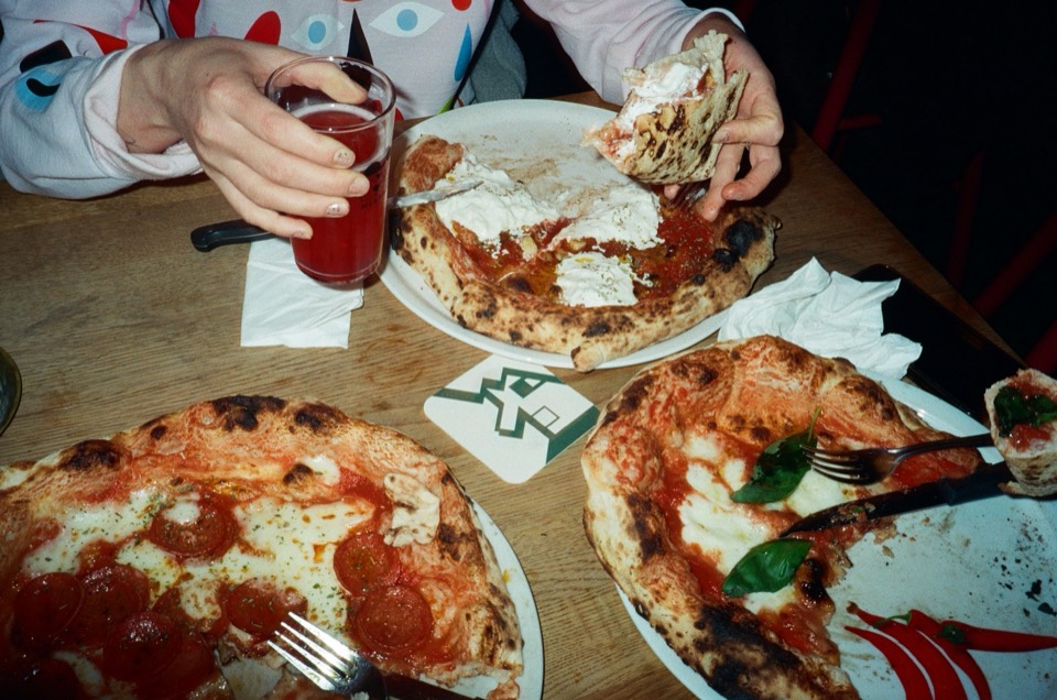 Friends sharing pizzas across a wooden table